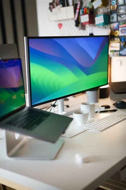 A photographer working at a creative setup with a laptop and Wacom tablet, focused on editing photos indoors.